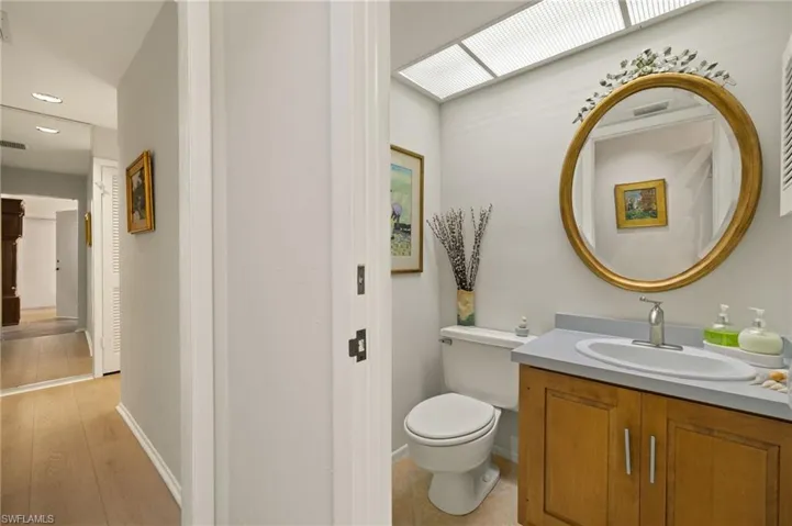 Bathroom featuring baseboards, vanity, toilet, and wood finished floors