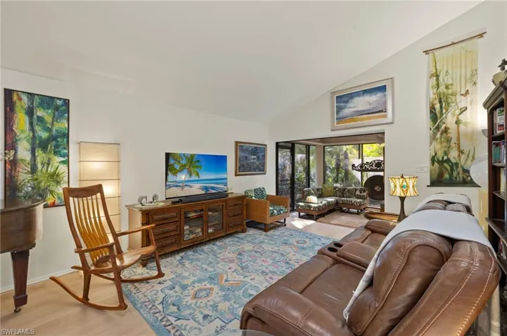 Living room featuring high vaulted ceiling, baseboards, and wood finished floors