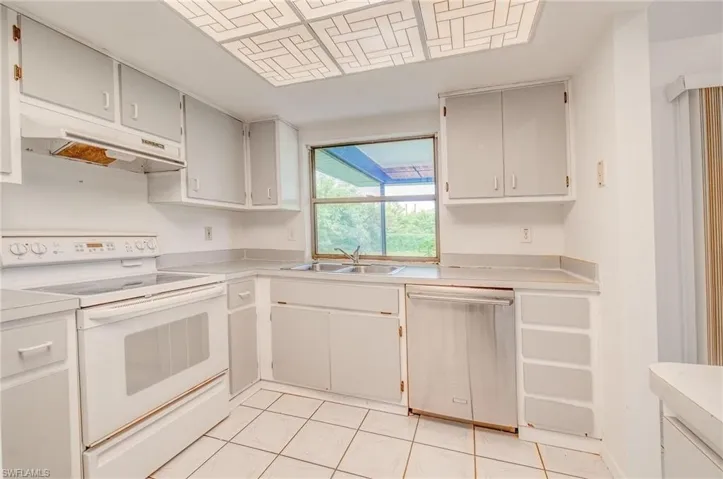 Kitchen with gray cabinetry, sink, white electric range oven, light tile patterned flooring, and dishwasher