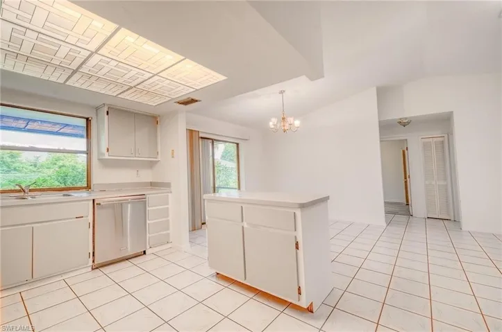 Kitchen with white cabinetry, light tile patterned floors, dishwasher, pendant lighting, and sink