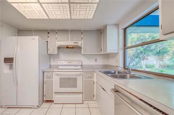 Kitchen featuring sink, white appliances, and light tile patterned floors