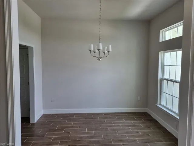 Spare room featuring a chandelier, healthy amount of natural light, and baseboards