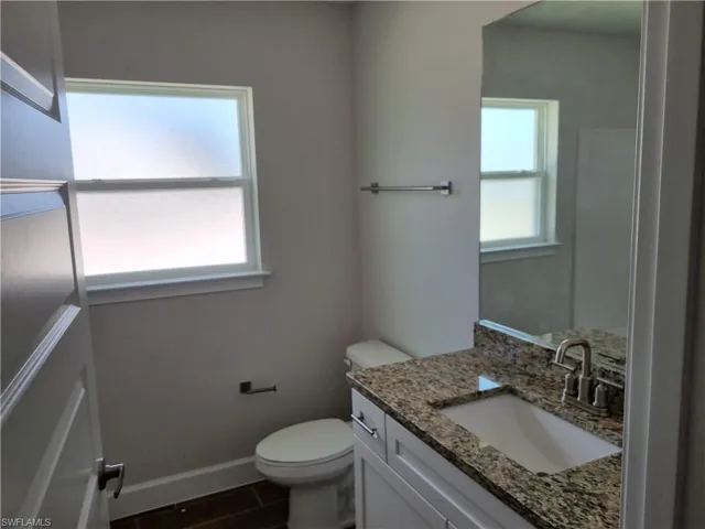 Bathroom with vanity, toilet, baseboards, and wood finished floors