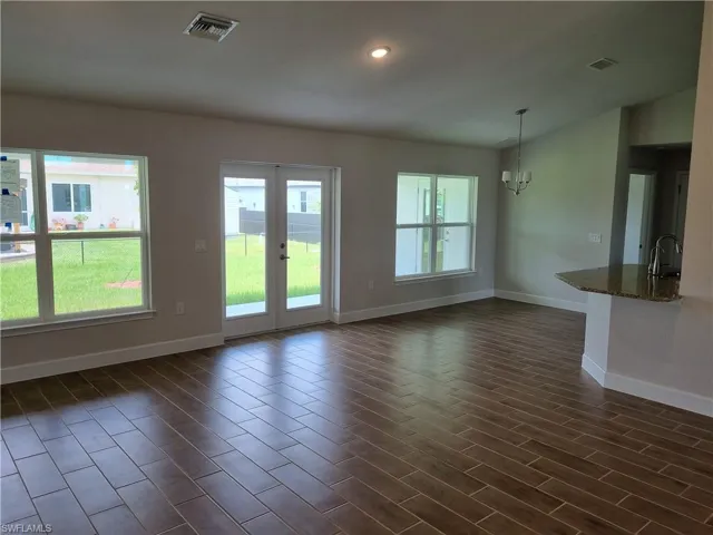 Unfurnished living room with baseboards, dark wood finished floors, a chandelier, a sink, and recessed lighting