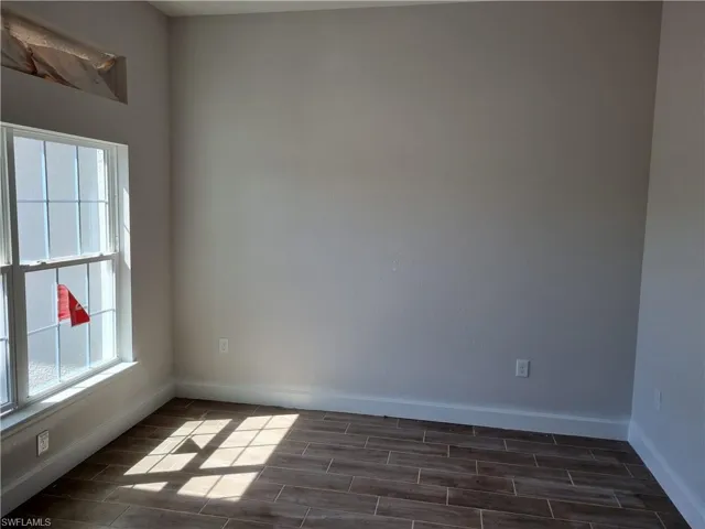 Unfurnished room with a healthy amount of sunlight, wood tiled floor, and baseboards