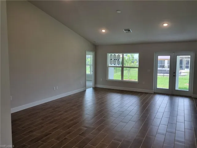 Empty room featuring baseboards, french doors, recessed lighting, vaulted ceiling, and dark wood finished floors