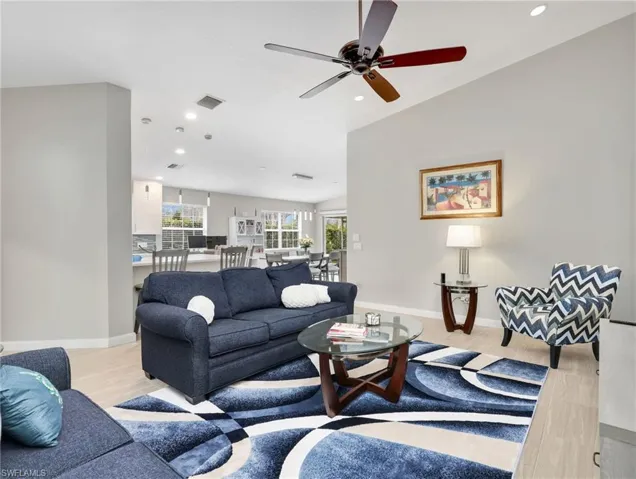 Living area with vaulted ceiling, a ceiling fan, light wood finished floors, and recessed lighting