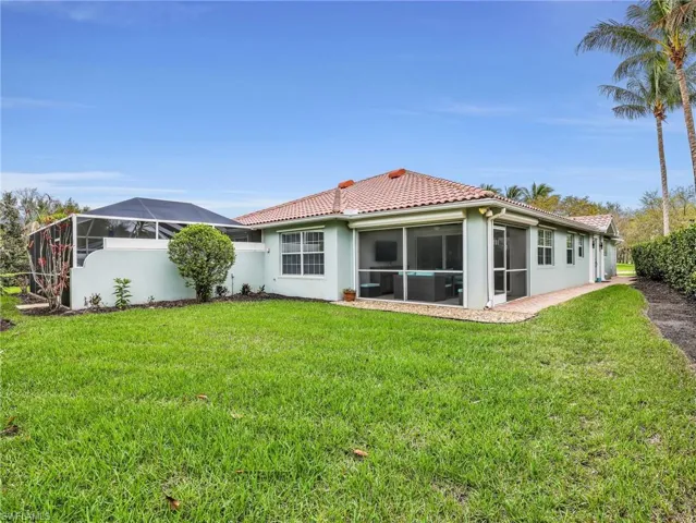 Back of house with a sunroom, a yard, a tile roof, and stucco siding