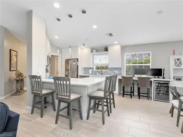 Kitchen featuring a breakfast bar area, a peninsula, stainless steel appliances, white cabinets, and tasteful backsplash