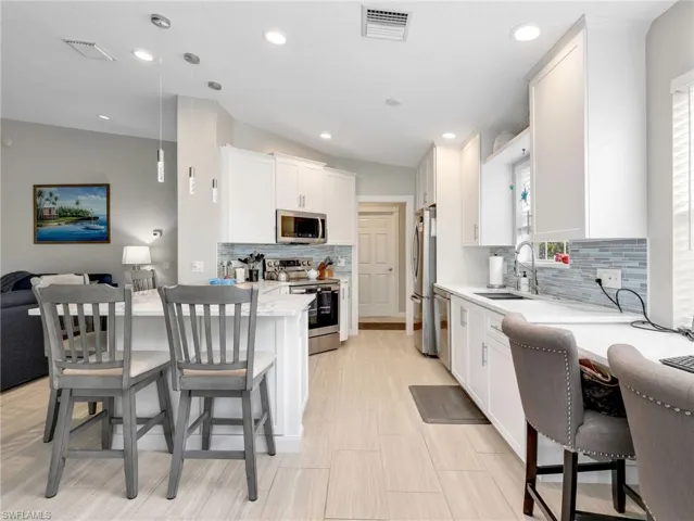 Kitchen with a kitchen breakfast bar, decorative light fixtures, stainless steel appliances, and a peninsula