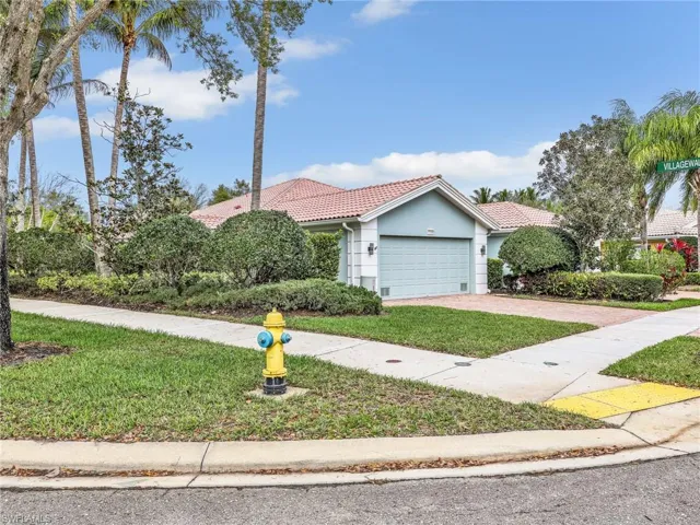View of front of home featuring a tile roof, driveway, a front yard, and an attached garage
