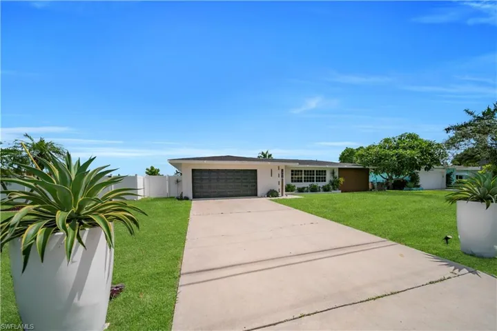 Ranch-style home featuring a garage, driveway, and stucco siding