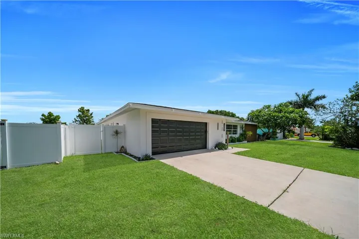 View of front of property with an attached garage, driveway, and stucco siding
