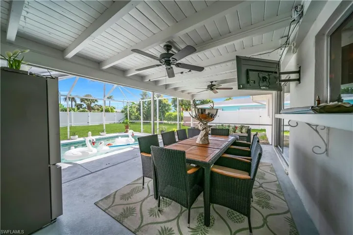 Fenced backyard with ceiling fan, glass enclosure, a patio area, and outdoor dining space