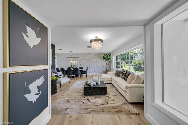 Living area featuring wallpapered walls, a chandelier, wood finished floors, and an accent wall