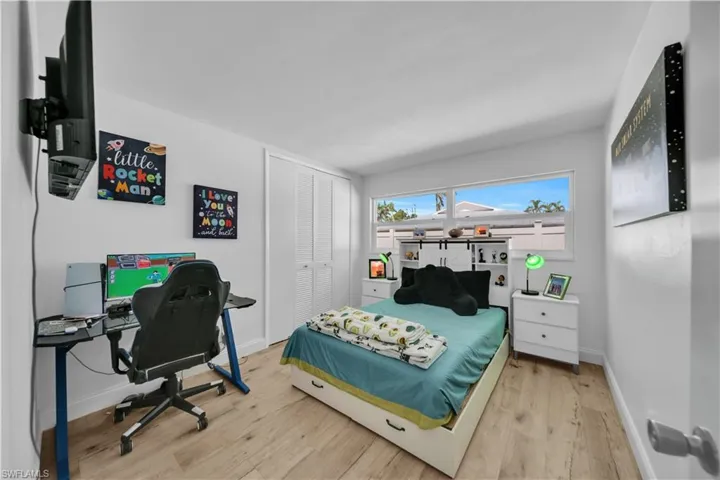 Bedroom featuring wood finished floors, a closet, and a desk