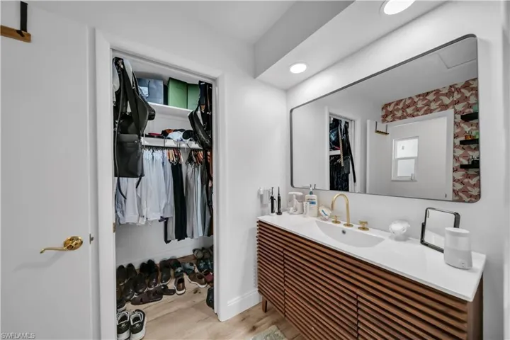 Bathroom with vanity, a spacious closet, and wood finished floors