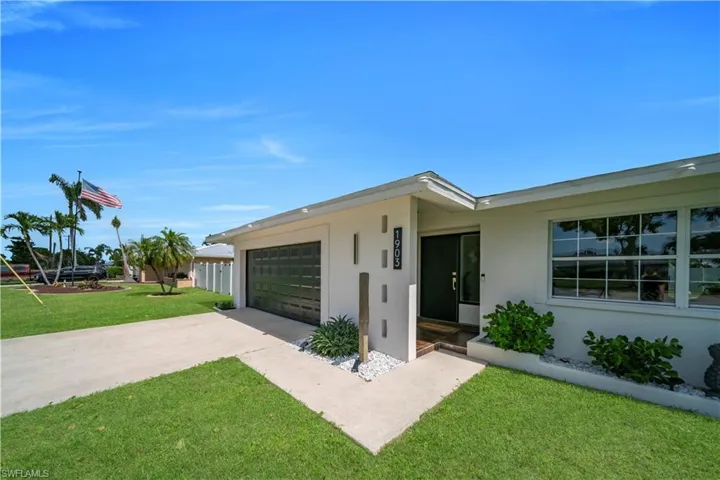Single story home featuring driveway, an attached garage, stucco siding, and a front lawn