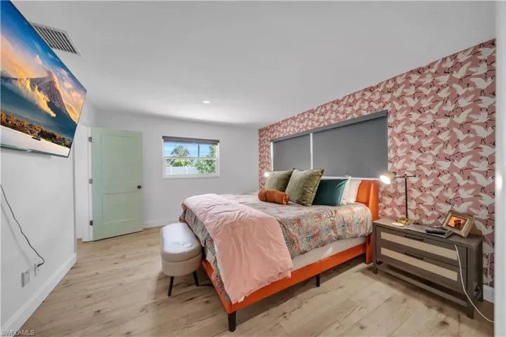 Bedroom featuring wood finished floors, wallpapered walls, and an accent wall