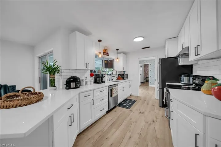 Kitchen featuring electric stove, dishwasher, a peninsula, decorative backsplash, and white cabinetry