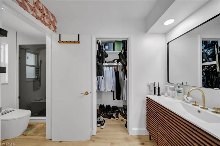 Bathroom featuring vanity, a spacious closet, wood finished floors, and a shower stall