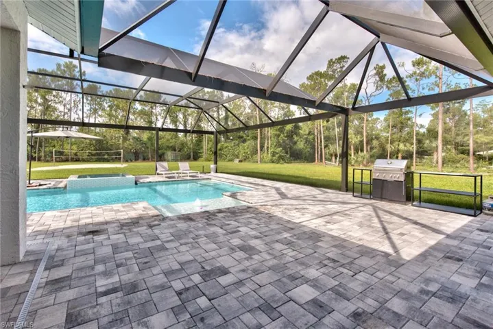 View of swimming pool with an in ground hot tub, a yard, area for grilling, a patio area, and a lanai