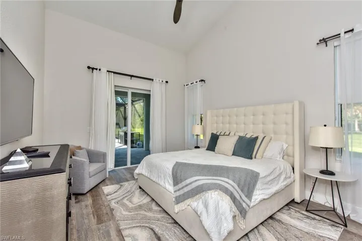Bedroom featuring ceiling fan, hardwood / wood-style flooring, high vaulted ceiling, and access to exterior