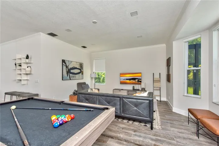 Recreation room featuring a textured ceiling, hardwood / wood-style flooring, ornamental molding, and pool table
