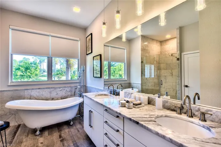 Bathroom featuring plus walk in shower, tile walls, vanity, and wood-type flooring