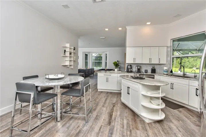 Kitchen with light hardwood / wood-style flooring, backsplash, a kitchen island, white cabinets, and sink