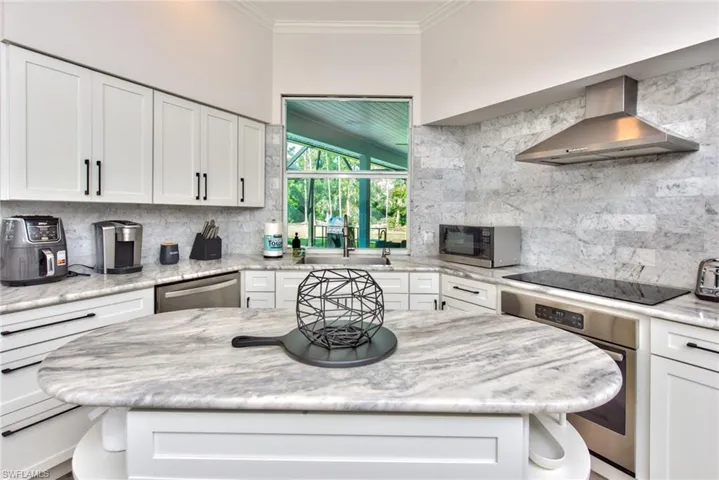 Kitchen with appliances with stainless steel finishes, wall chimney range hood, sink, and white cabinets