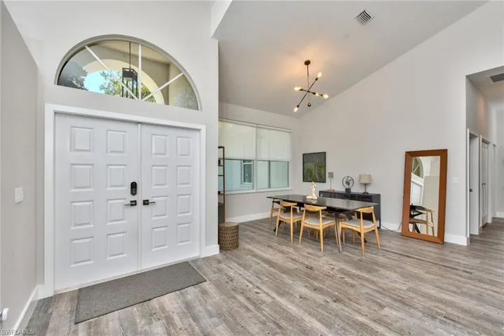 Entrance foyer with hardwood / wood-style flooring, a notable chandelier, and high vaulted ceiling