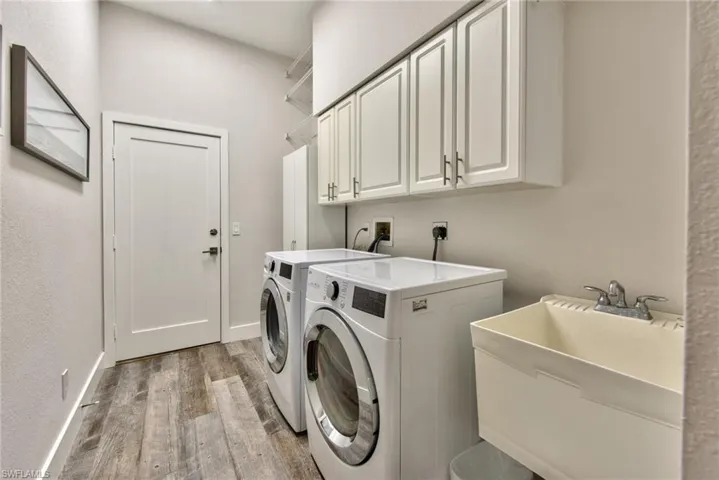 Laundry room featuring hardwood / wood-style floors, sink, washer and dryer, and cabinets