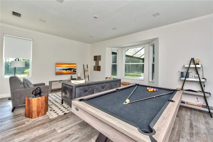 Recreation room with pool table, wood-type flooring, and crown molding