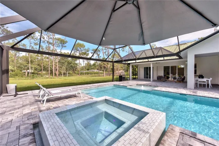 View of swimming pool with an in ground hot tub, a lanai, a patio area, and a yard