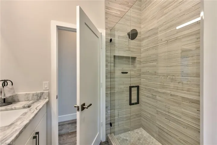 Bathroom featuring a shower with shower door and vanity