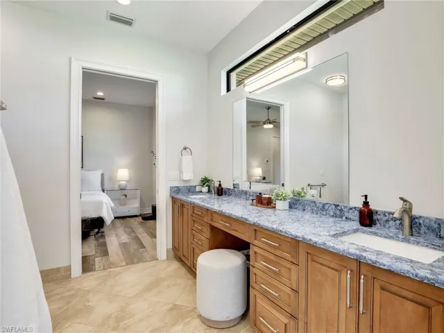 Bathroom featuring double vanity, ensuite bathroom, light tile patterned floors, and recessed lighting