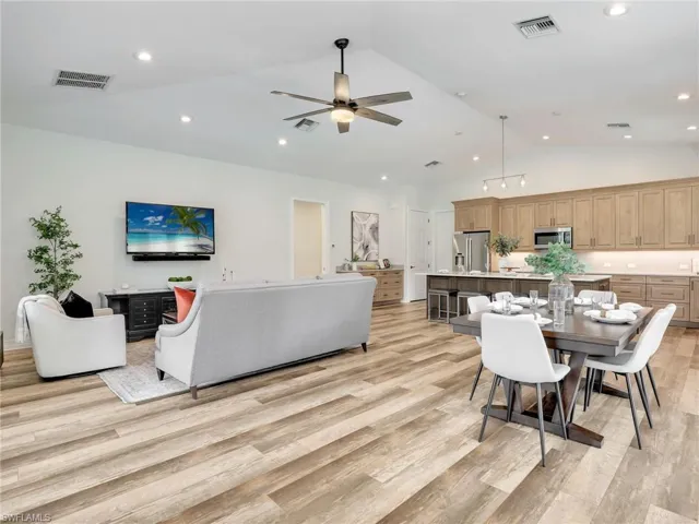 Living area with light wood-style flooring, high vaulted ceiling, a ceiling fan, and recessed lighting