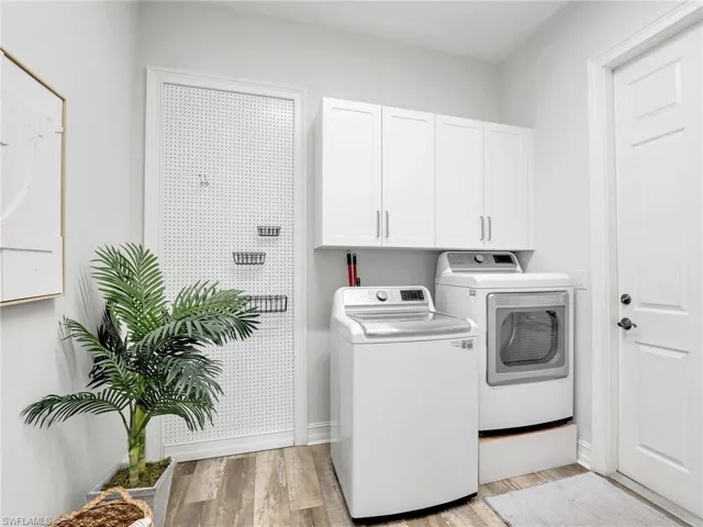 Laundry area featuring light wood-style floors, cabinet space, and washer and clothes dryer