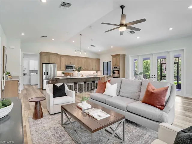 Living area with vaulted ceiling, light wood-type flooring, recessed lighting, washer / dryer, and french doors