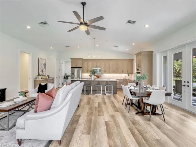 Living room with lofted ceiling, light wood finished floors, ceiling fan, and recessed lighting