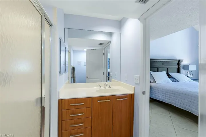 Ensuite bathroom featuring a shower stall, vanity, and light tile patterned floors