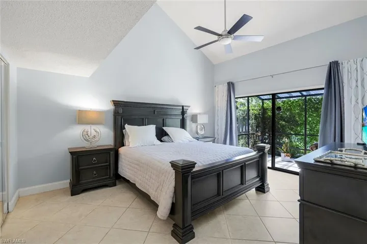 Bedroom with access to exterior, high vaulted ceiling, light tile patterned floors, a ceiling fan, and a textured ceiling