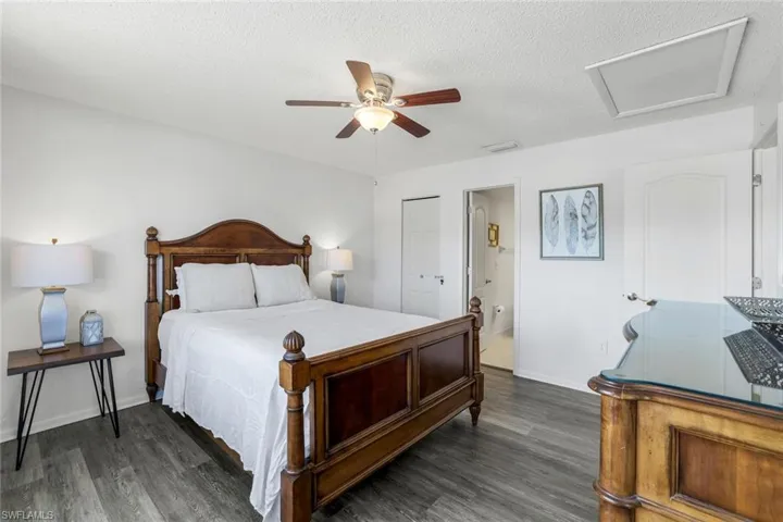Bedroom with attic access, dark wood-style flooring, a ceiling fan, a textured ceiling, and a closet
