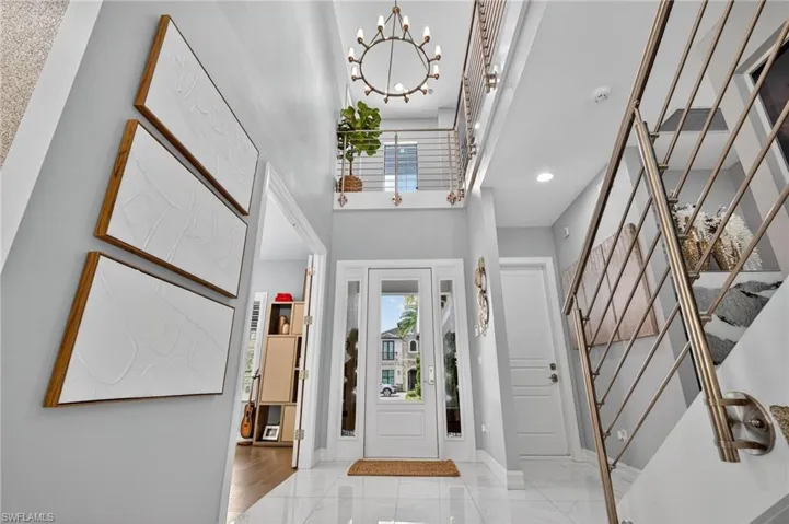 Foyer featuring a chandelier, light marble finish floors, and a towering ceiling