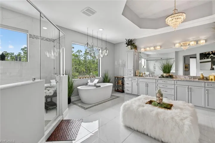 Full bathroom featuring vanity, a shower stall, a freestanding bath, and a chandelier