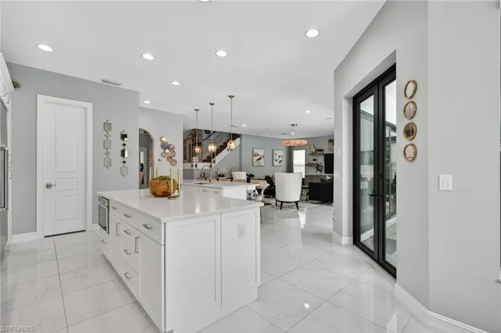 Kitchen with white cabinetry, hanging light fixtures, a center island, recessed lighting, and light marble finish floors