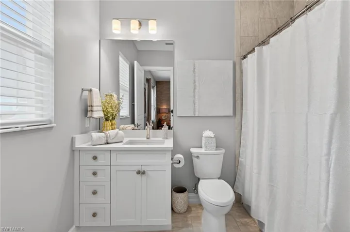 Full bath with vanity, curtained shower, and plenty of natural light