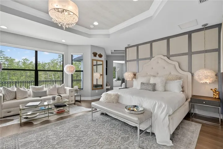Bedroom with a tray ceiling, wood finished floors, ornamental molding, recessed lighting, and a chandelier