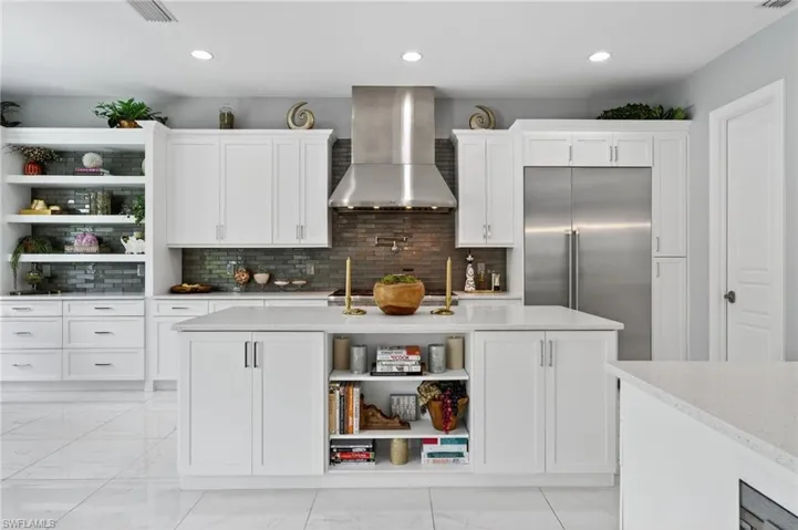 Kitchen featuring open shelves, backsplash, wall chimney exhaust hood, built in refrigerator, and white cabinetry